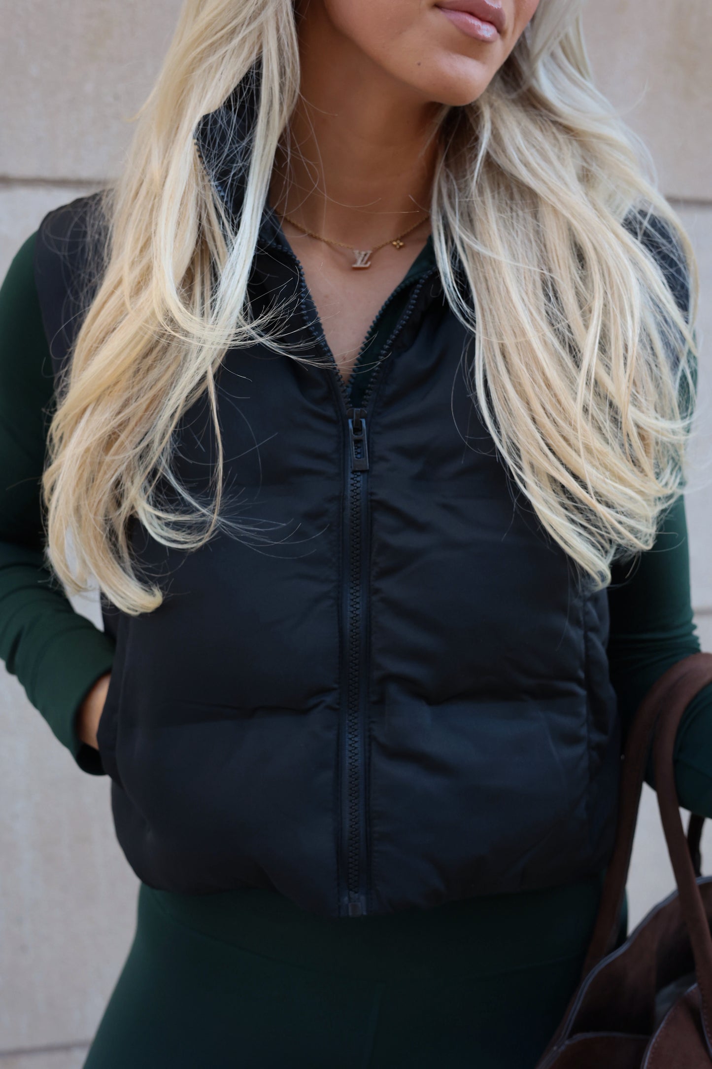 Person wearing a black puffer vest with a neutral background
